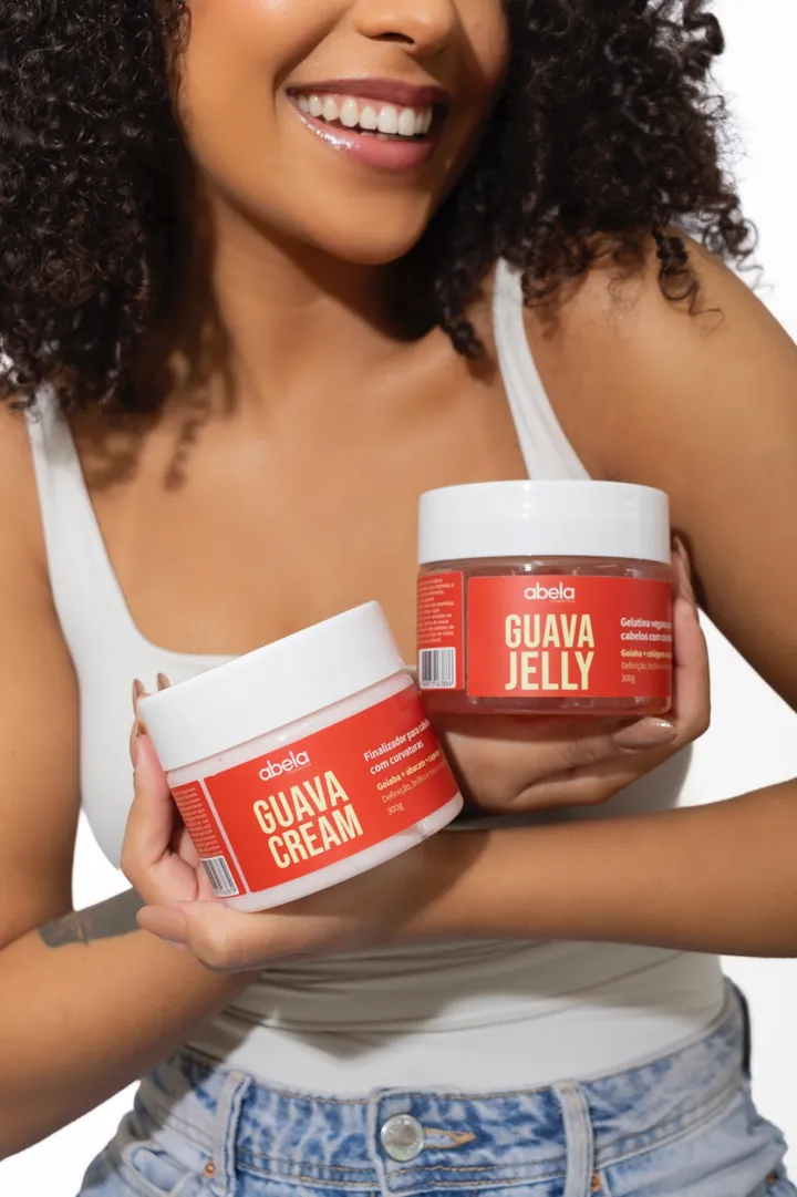 Guava Cream e Guava Jelly da Abela, dois potes vermelhos de 300g, segurados por uma modelo sorrindo.